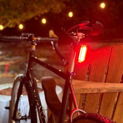 Rear bike tail light leaning against a wooden chair at night