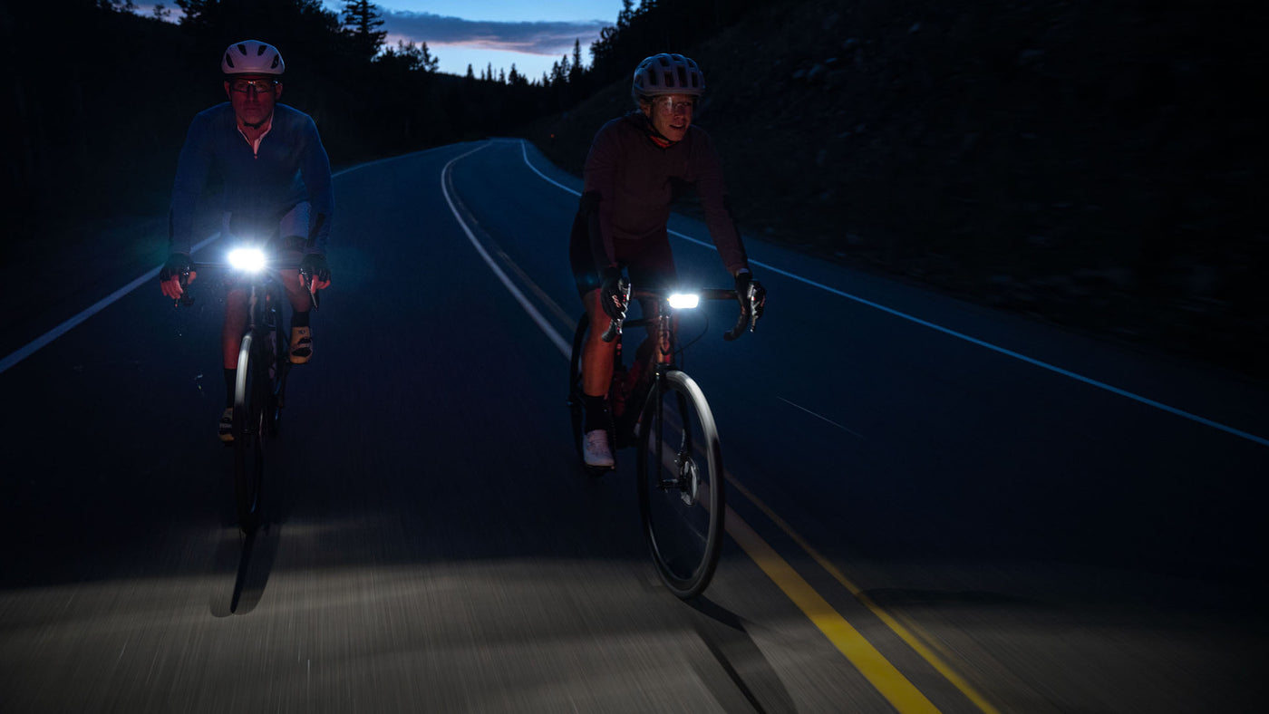 Two bike riders at night on the road with Detour bike light on their handlebars