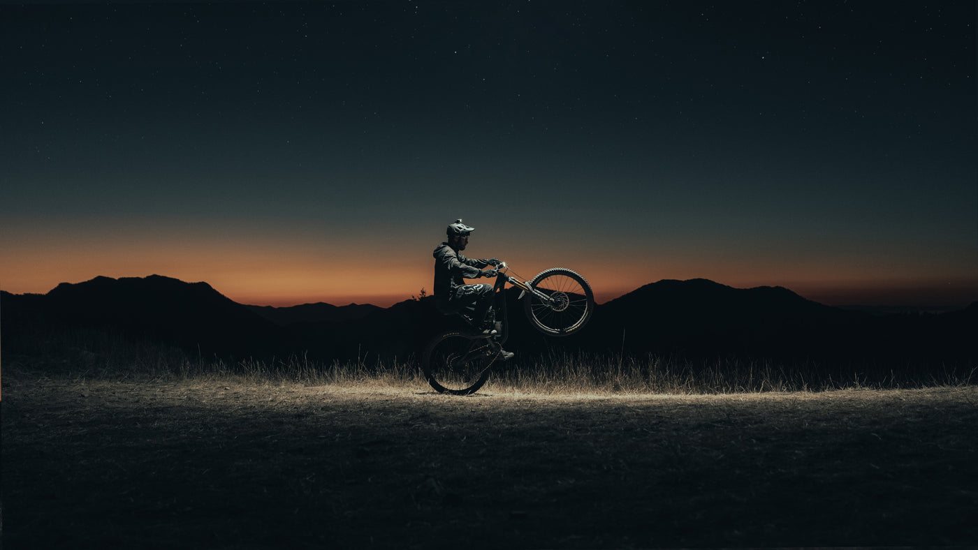 bike rider doing a wheelie at night with two bike lights