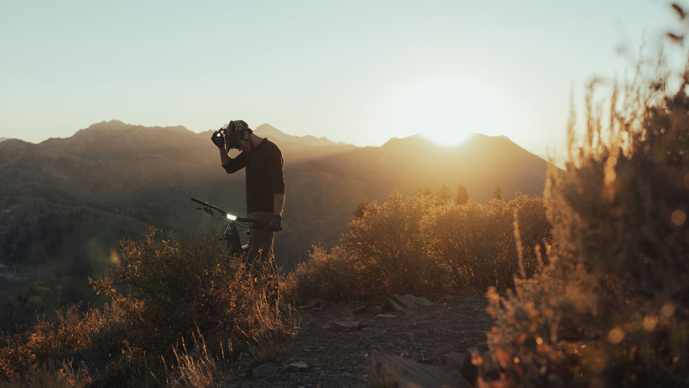 Bike rider checking his lights while on top of a mountain