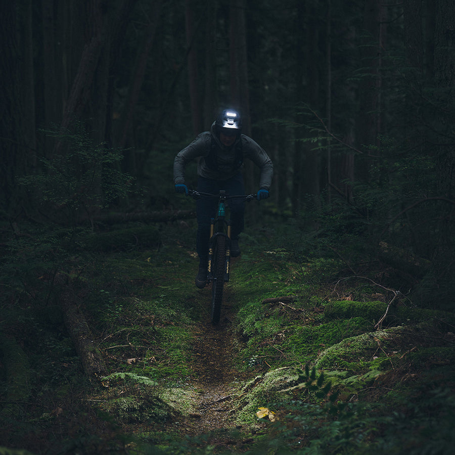 Rider using Portal helmet light on a dark forest trail